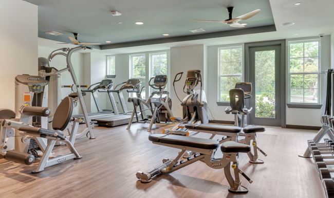 The fitness center at our apartments for rent in Dallas, featuring wood grain floor paneling and exercise equipment.
